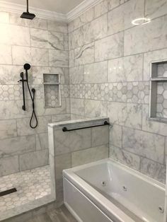 a bathroom with white marble walls and flooring, including a bathtub next to a walk in shower