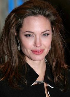 a close up of a person wearing a suit and tie with earrings on her head