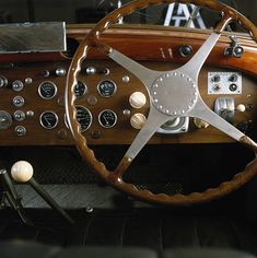 the steering wheel and dashboard of an old fashioned sports car with wood grained dash boards