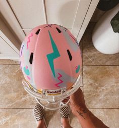 a person wearing a pink helmet with lightning bolt designs on it, while standing in front of a door