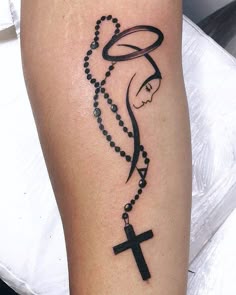 a woman's leg with a rosary and a cross tattoo on the side of her leg