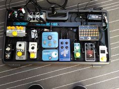 an assortment of pedals and amps in a black case on the floor next to a pair of shoes