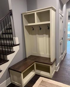 an entryway with built - in benches and storage cabinets on either side of the stairs