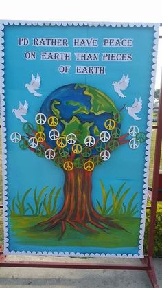 a sign with peace on it in front of a tree and birds flying around the tree