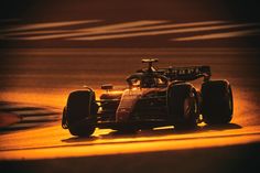 a racing car driving on a track at night time with the sun shining behind it