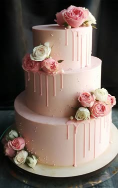 a three tiered cake with pink icing and flowers on it's side