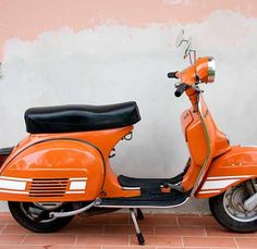 an orange scooter parked in front of a wall