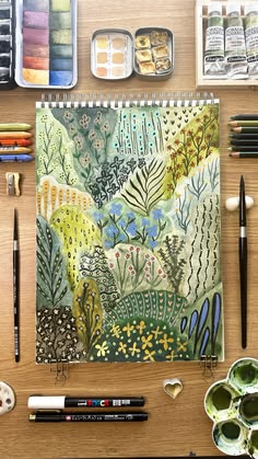 a wooden table topped with lots of art supplies