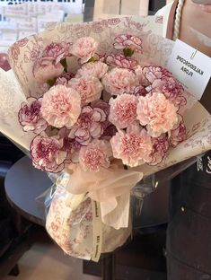 a bouquet of pink carnations wrapped in paper