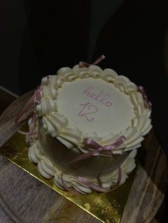a cake that is sitting on a table with ribbon around the edges and writing hello to us