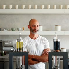 a man standing in front of a counter with two blenders on top of it