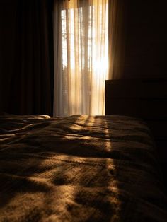 the sun is shining through curtains onto a bed