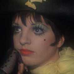 a woman wearing a black hat and yellow dress with words written on the side of her face