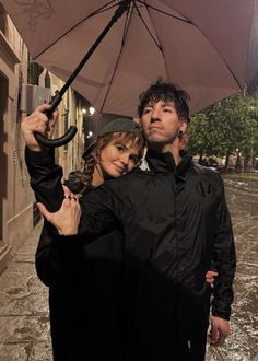 a man and woman standing under an umbrella in the rain