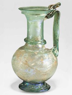 a green glass vase with a handle on it