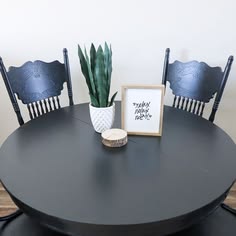 a black table with two chairs and a potted plant on top of the table