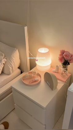 a white night stand with pink flowers on it next to a bed and nightstand in a bedroom