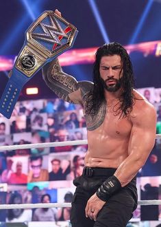 a man with long hair holding up a wrestling belt