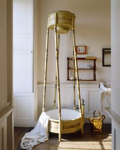 an old fashioned bathtub in the corner of a room with white walls and wood flooring
