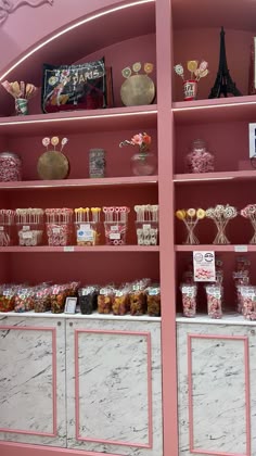 the shelves are filled with sweets and candies in pink, white and gold colors