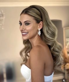 a woman in a white dress with long hair and diamond earrings on her left shoulder