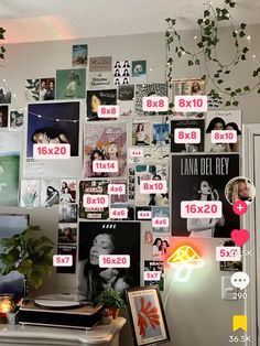 a wall covered in posters and pictures next to a desk with a computer on it