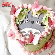 a cake decorated with pink and green icing has a totoro face on it