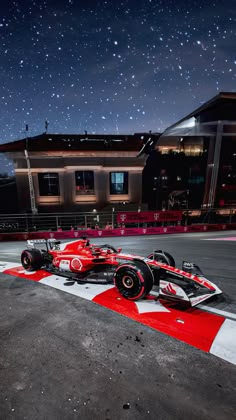 a red and white race car parked in front of a building with stars above it