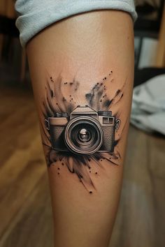 a tattoo with a camera on it's leg and some ink splatters