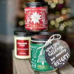 three jars of holiday candles on a wooden table