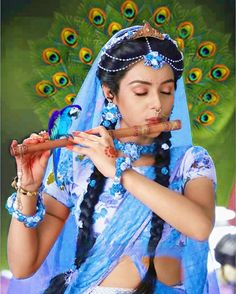 a woman dressed in blue and holding a stick with peacocks on it's head