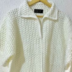 a white sweater hanging on a wooden hanger