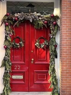 a red door decorated with greenery and christmas decorations