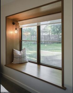 a window seat with pillows on it in front of a sliding glass door that leads to a yard