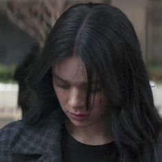 a woman with long black hair looking down at her cell phone