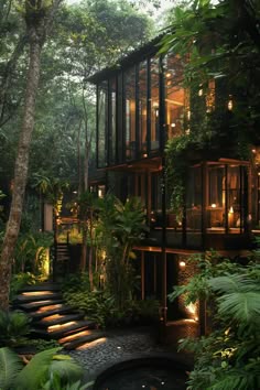 the house is surrounded by lush greenery and lit up at night with lights on