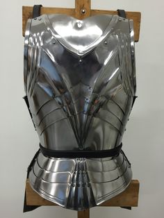 a metal armor sitting on top of a wooden stand