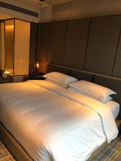 a large bed sitting in a bedroom next to a night stand with two lamps on it