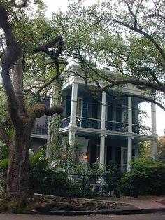 a large white house sitting next to a lush green tree