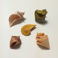 four origami umbrellas sitting on top of a white table next to each other