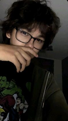 a young man wearing glasses and holding his hand on top of the laptop computer screen