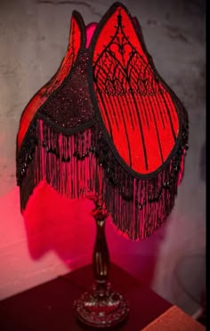 two red lamps with black fringes are on a table