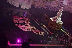 a large cake sitting on top of a table in front of a crowd at a party