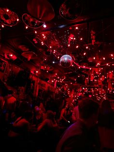 a group of people in a dark room with disco balls hanging from the ceiling and lights on the ceiling