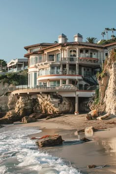 an ocean front home on the beach with waves coming in from the water and people walking around
