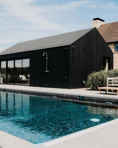 a house with a pool in front of it and a wooden bench next to it