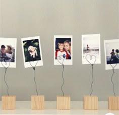 four pictures are placed on wooden blocks with wire attached to them, along with two small hearts