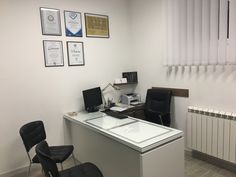 an office with a desk, chair and pictures on the wall