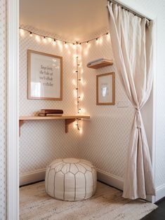a small room with lights on the wall and a round ottoman in front of it