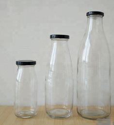 three empty glass bottles sitting on top of a wooden table